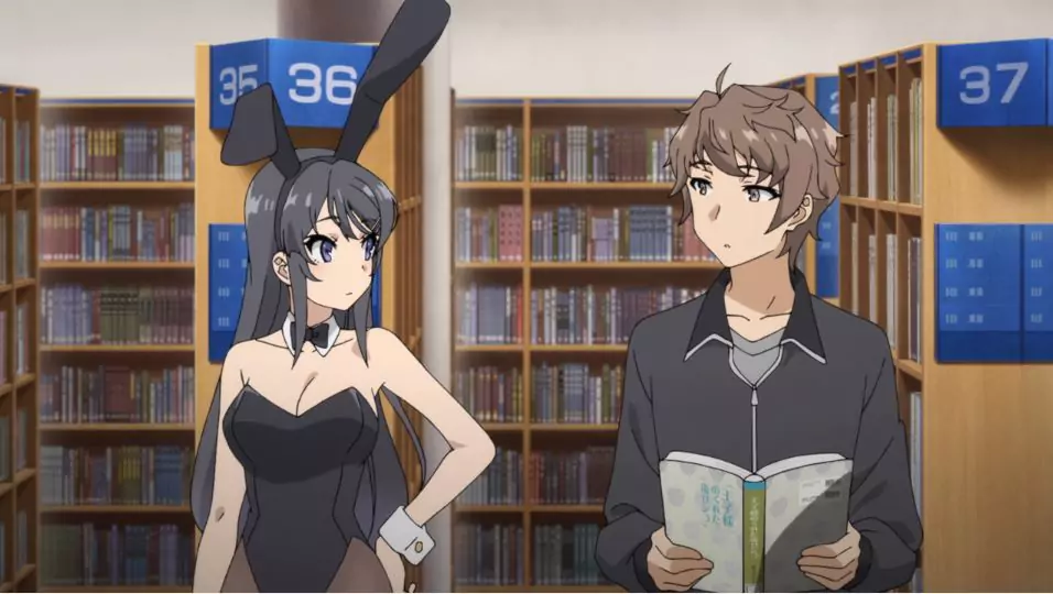 Mai Sakurajima appears in a bunny suit while talking to Sakuta Azusagawa in a quiet library scene from the anime Rascal Does Not Dream.
