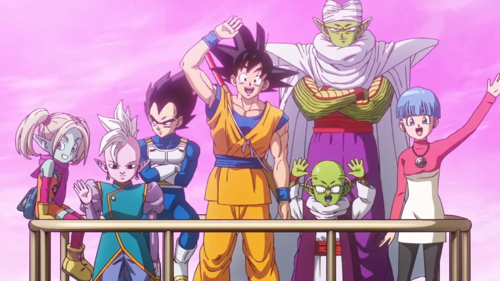 Main characters from Dragon Ball Super standing together against a pink background. From left to right: Bulma, Supreme Kai, Vegeta, Goku in his orange gi, Piccolo in his white cape and turban, Dende, and Bulma's son Trunks with blue hair. 