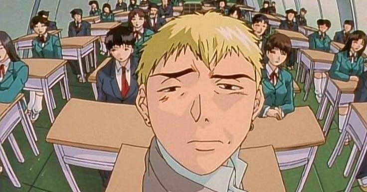 Protagonist of classic comedy anime, Onizuka smirking at the camera while seated in a classroom full of students.