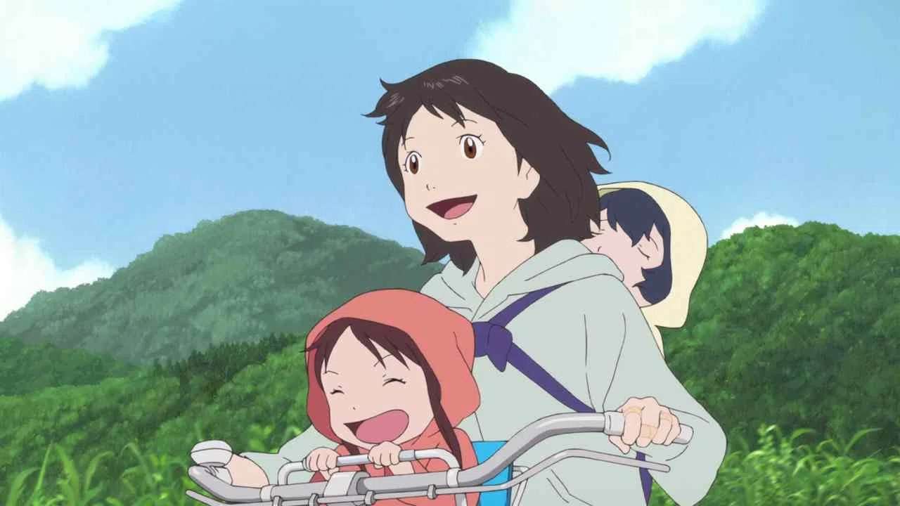 A joyful mother rides a bicycle through the countryside with her two children from the film Wolf Children.
