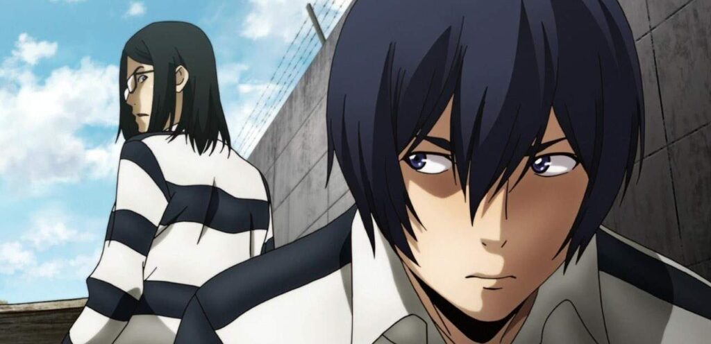 Characters from Prison School in prison uniforms exchange suspicious glances near a wall topped with barbed wire.